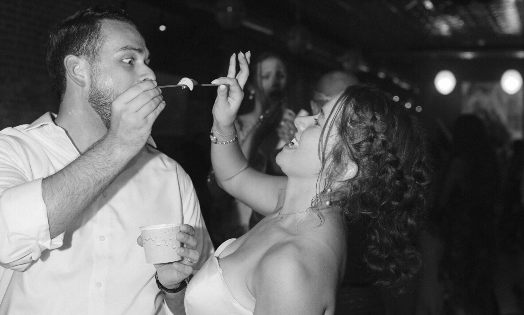 Fun wedding reception couple shows bride and groom sharing a bite of dessert together.