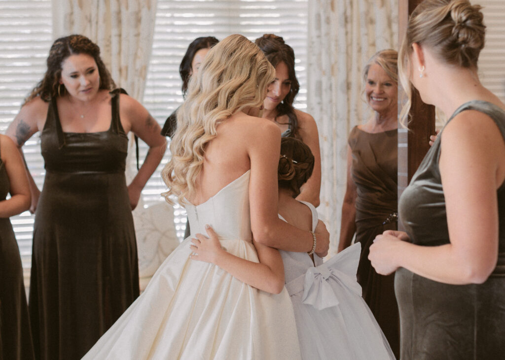 Flower girl hugs bride while they get ready for the wedding day