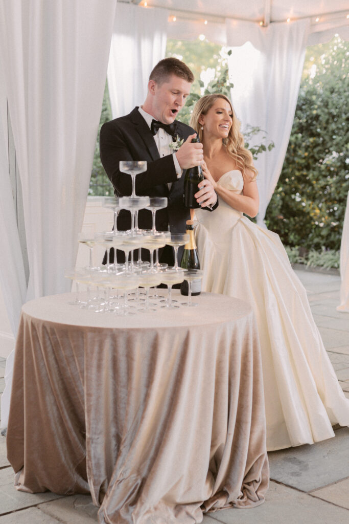 Couple pops a bottle of champagne at their wedding reception