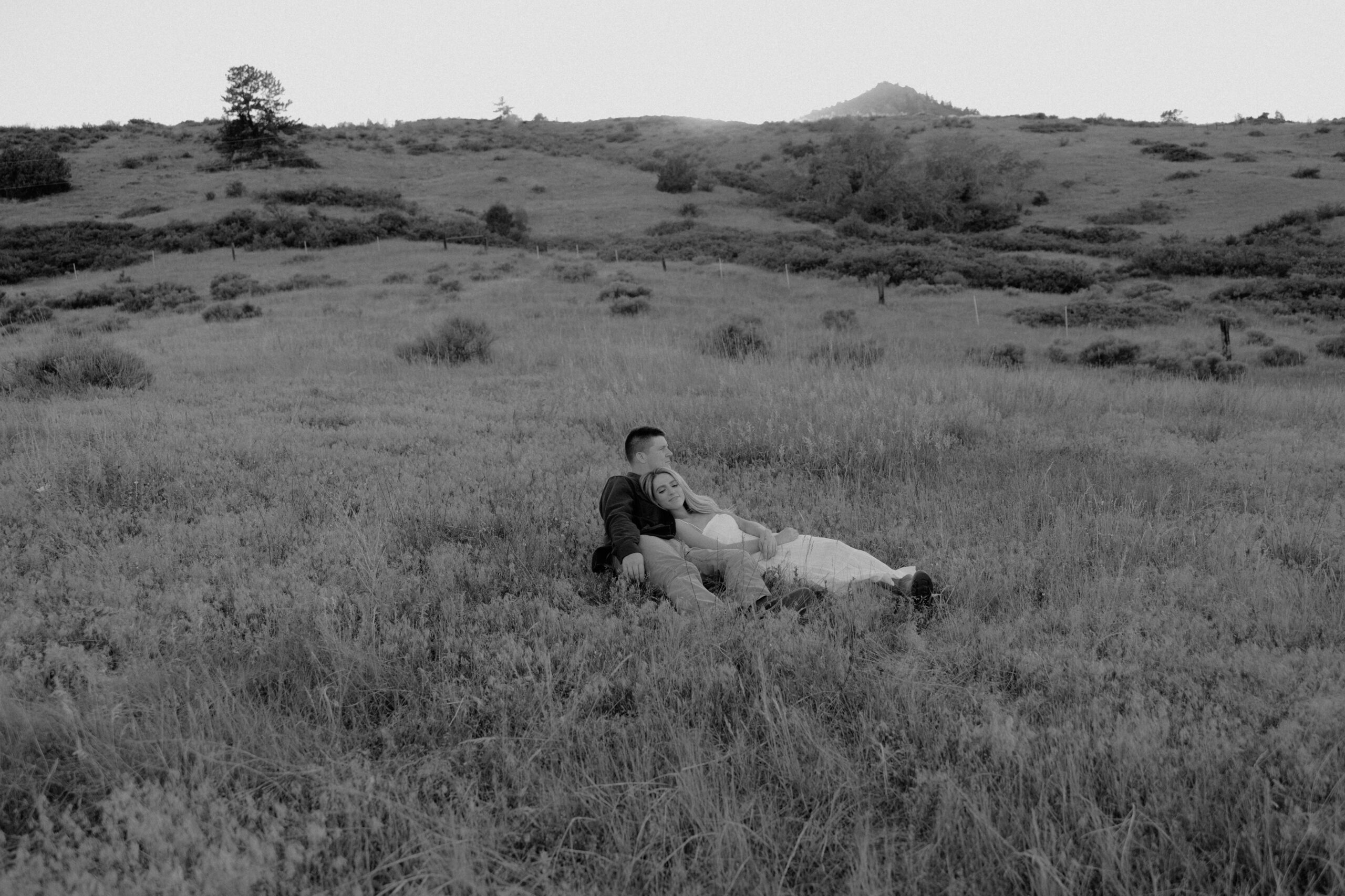 couple lays comfortably in a field gazing off into the distance