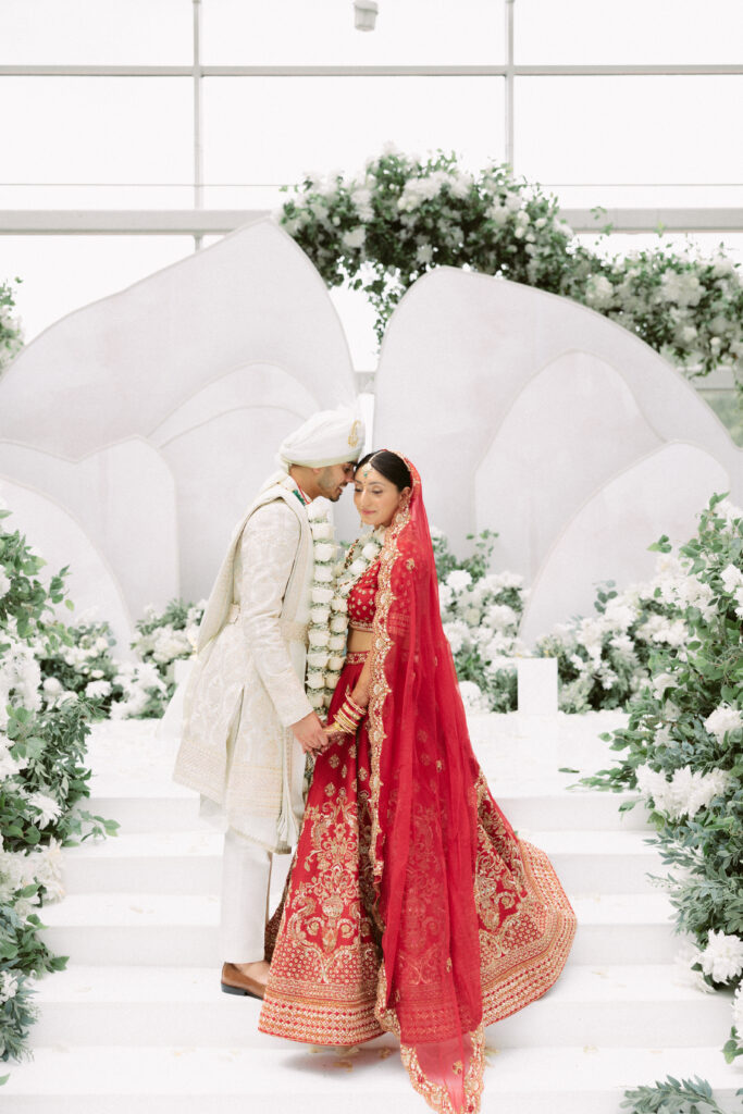 Indian bride and groom pose romantically on the steps leading up to their mandap