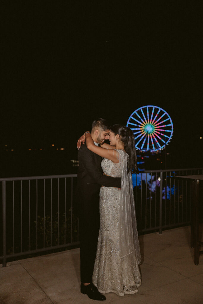 South Asian couple poses with the ferris wheel from the National Gaylord and Resort in background