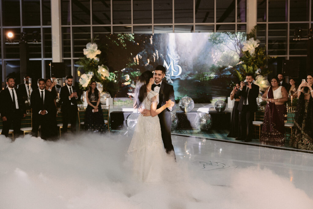 Bride and groom share their first dance surrounded by clouds of fog during their elegant South Asian wedding reception at the Gaylord National Resort.
